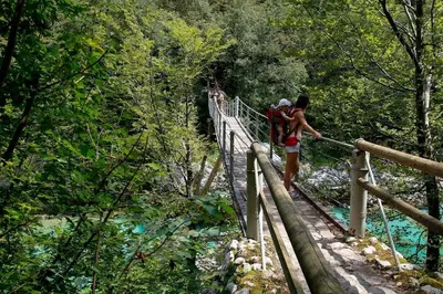 two people on a suspension bridge over a river at Apartma na podeželju - Slovenia Nature in Kanal