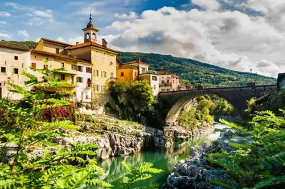 a bridge over a river in front of buildings at Apartma na podeželju - Slovenia Nature in Kanal