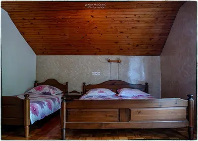 a bedroom with two beds and a wooden ceiling at Turistična kmetija Markun in Golnik
