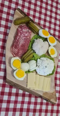 a plate of food with eggs sausage vegetables and cheese at Soba tete Tile - Hiša ob gozdu in Ptuj