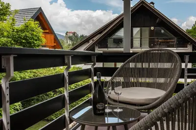 a table and chairs on a balcony with a bottle of wine at Apartments Villa AnnaMaria in Bled