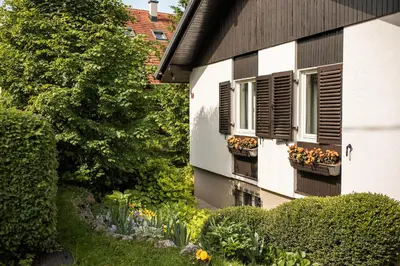 a garden in front of a house with flowers and windows at Apartments Villa AnnaMaria in Bled