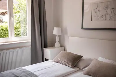 a white bedroom with a bed and a window at Apartments Villa AnnaMaria in Bled