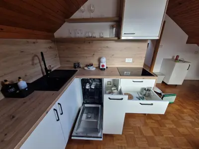 a small kitchen with white cabinets and wooden walls at Zoya Bled Apartments in Bled