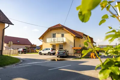 a house with two cars parked in a parking lot at Apartments Galunder in Veržej
