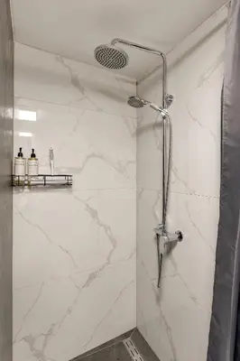 a bathroom with a shower with white marble walls at Superior Holiday Home Fortuna in Čatež ob Savi