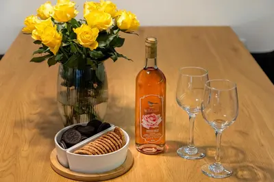 a table with a bottle of wine and a vase of yellow roses at Superior Holiday Home Fortuna in Čatež ob Savi