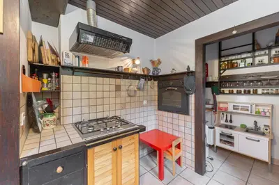 a small kitchen with a stove and a red stool at First House - Lovely Holiday Home near Cerknica in Nova Vas