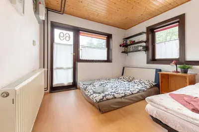 a bedroom with a bed and two windows at First House - Lovely Holiday Home near Cerknica in Nova Vas