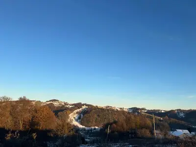 a snow covered hill with a river on it at Ana Apartment in Gradišča