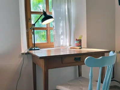 a desk with a lamp and a chair in front of a window at Vineyard cottage Kovačnica in Semič
