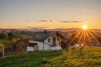 a house on a hill with the sun setting at Cottage in Novo Mesto 50797 in Novo Mesto