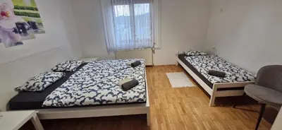 a bedroom with two beds and a chair and a window at Apartma Pers in Zgornje Gorje