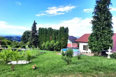 a garden with trees and a house in a field at Apartma Grlica in Selnica ob Muri