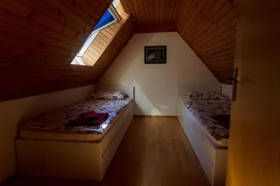 a attic bedroom with two beds and a window at Domačija Marinč in Kostel