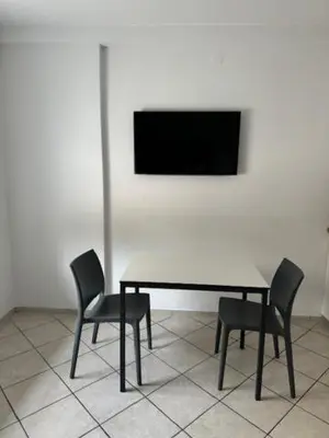 a table with two chairs and a television on a wall at Cozy flat near Tivoli park with free parking in Ljubljana