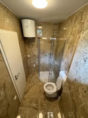 a bathroom with a toilet and a glass shower at Cozy flat near Tivoli park with free parking in Ljubljana