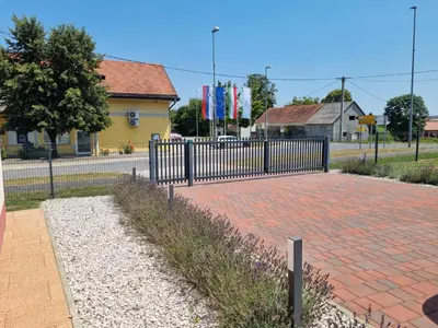 a fence in front of a brick sidewalk with purple flowers at Apartma Anci in Prosenjakovci