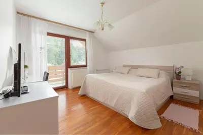 a white bedroom with a bed and a television at Fine Stay Apartments in Žirovnica