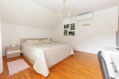 a white bedroom with a bed and a television at Fine Stay Apartments in Žirovnica