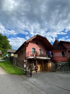 a pink house with a balcony on the side of it at Apartma Medvedjek in Velika Loka