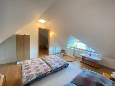 a attic bedroom with a bed and a window at Apartma Medvedjek in Velika Loka