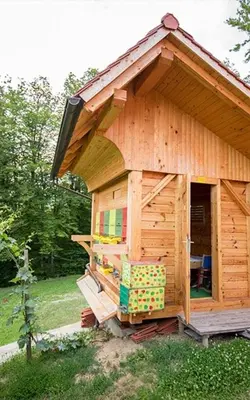 a small wooden play house in the grass at Apartma Medvedjek in Velika Loka