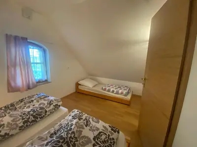 two beds in a small room with a window at Apartma Medvedjek in Velika Loka