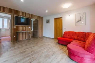 a living room with a red couch and a flat screen tv at Pogacar Apartments in Bled