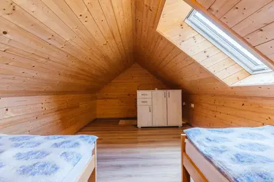 a wooden attic room with two beds and a window at Pogacar Apartments in Bled