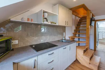 a kitchen with white cabinets and a sink and a staircase at Pogacar Apartments in Bled