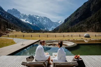 two people sitting in chairs on a deck with a pool at Villa Palenk Logar Valley in Solčava
