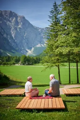 two people sitting on a picnic table looking at the mountains at Villa Palenk Logar Valley in Solčava