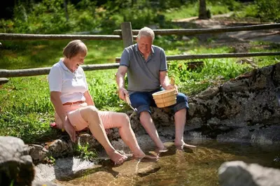 a man and woman sitting on a rock by a stream at Villa Palenk Logar Valley in Solčava