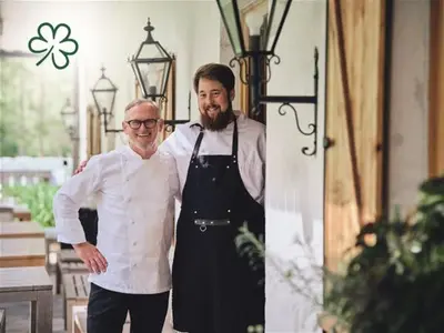 two men standing next to each other in a restaurant at Villa Palenk Logar Valley in Solčava