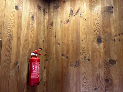 a red fire extinguisher on top of a wooden wall at Somova gora chalet in the woods in Kočevje