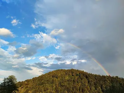 a rainbow in the sky over a hill at Red Riding Hood in Ljubljana