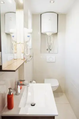 a white bathroom with a sink and a toilet at Hotel Šiška in Ljubljana