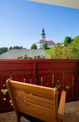 a wooden bench on a balcony with a lighthouse in the background at Turistična kmetija Pri Marku in Žabnica