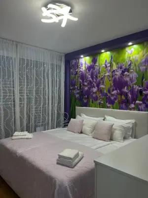a bedroom with a large bed with a flower mural on the wall at Apartment Anaa in Radovljica