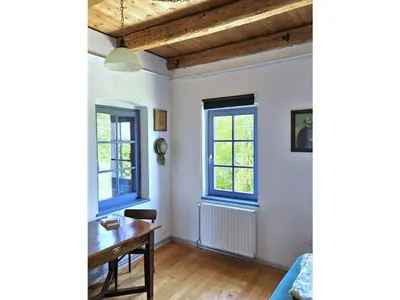 a living room with a table and two windows at Paulusberg Comfortable holiday residence in Ivanjkovci