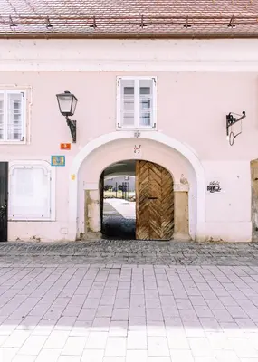 a pink building with a wooden door and an archway at Cozy flat in Center in Maribor