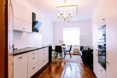 a kitchen with white cabinets and a dining room at Cozy flat in Center in Maribor