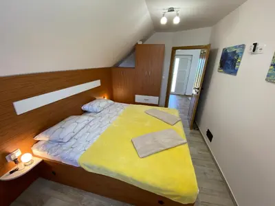 a bedroom with a large bed with a yellow blanket at Vineyard Cottage Joanna in Mirna Peč
