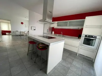 a kitchen with white cabinets and red walls at Apartma S in Sežana