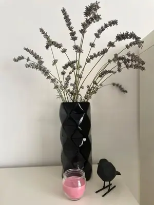 a black vase with flowers and a candle on a table at Apartma S in Sežana