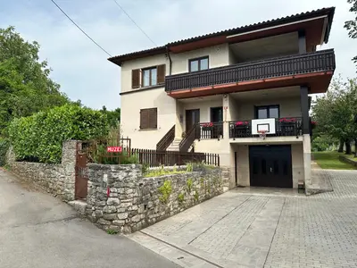 a house with a stone wall and a basketball hoop at Apartma S in Sežana