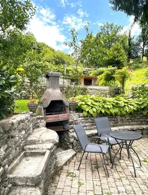 a patio with a table and two chairs and a stone oven at Apartma Savan in Tolmin