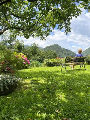 a woman sitting on a bench in a park at Apartma Savan in Tolmin