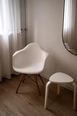 a white chair and a stool next to a mirror at Brodnik Apartment in Trbonje